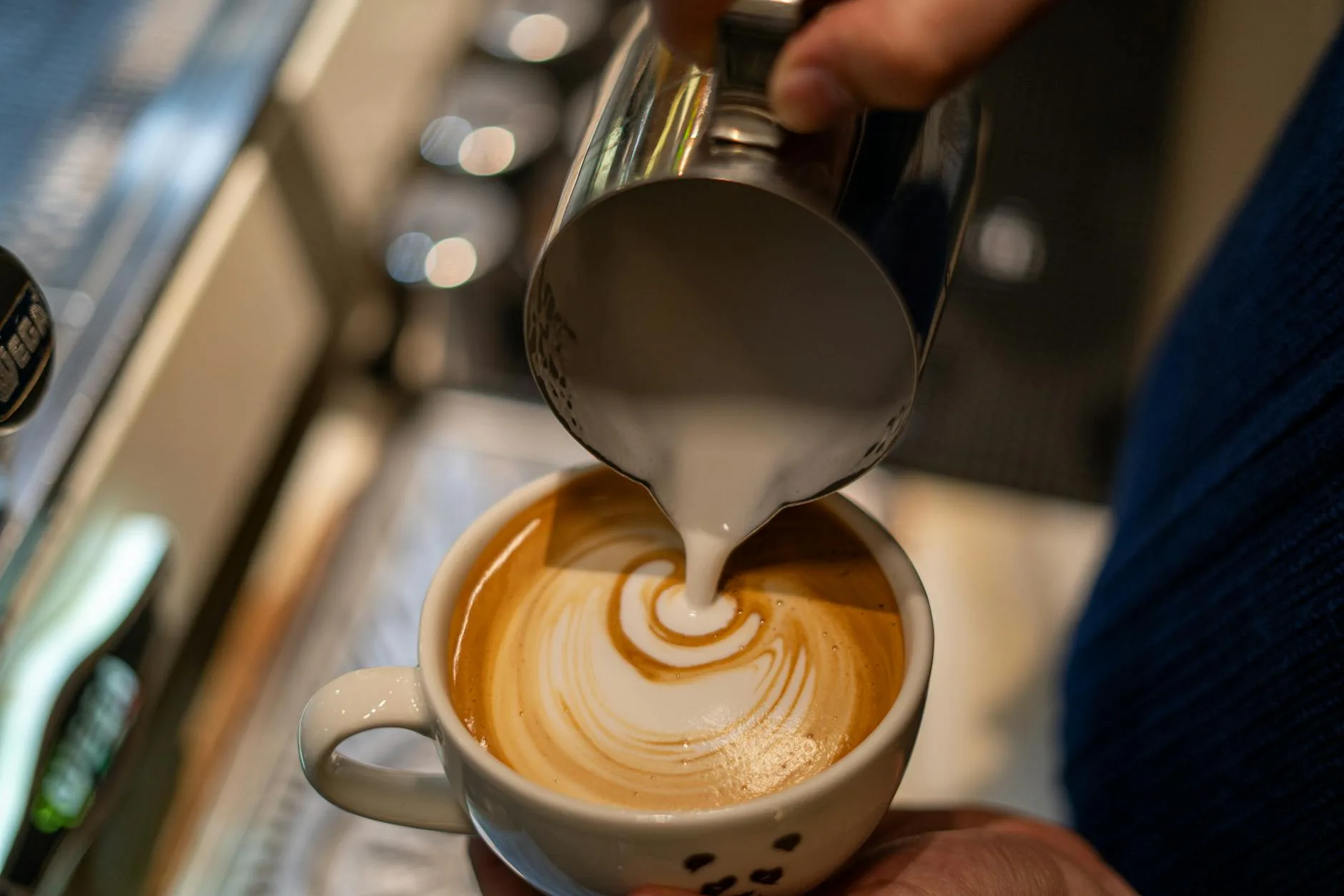 Barista steaming milk for latte art at a coffee machine