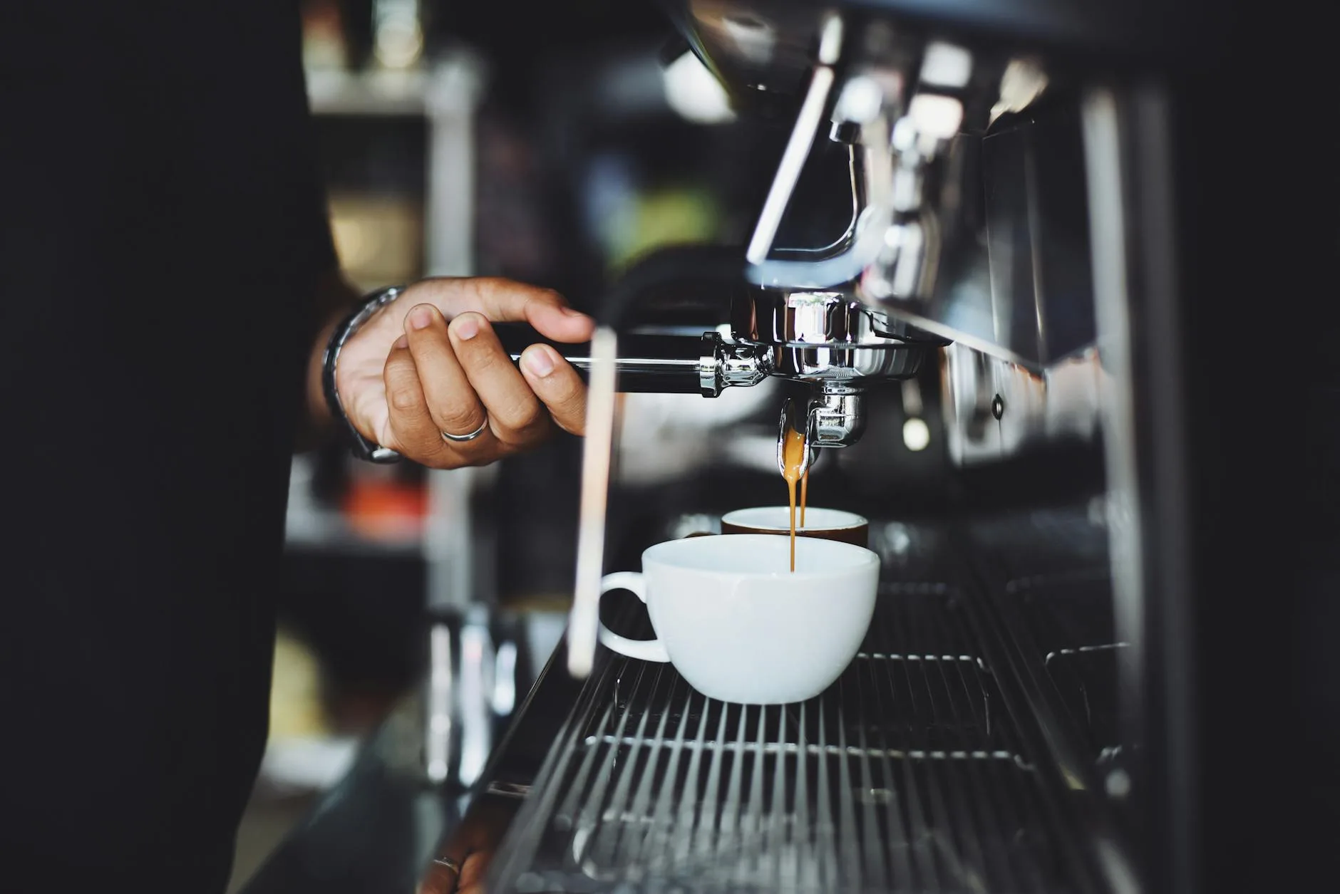 Espresso shot being pulled from a coffee machine into a cup