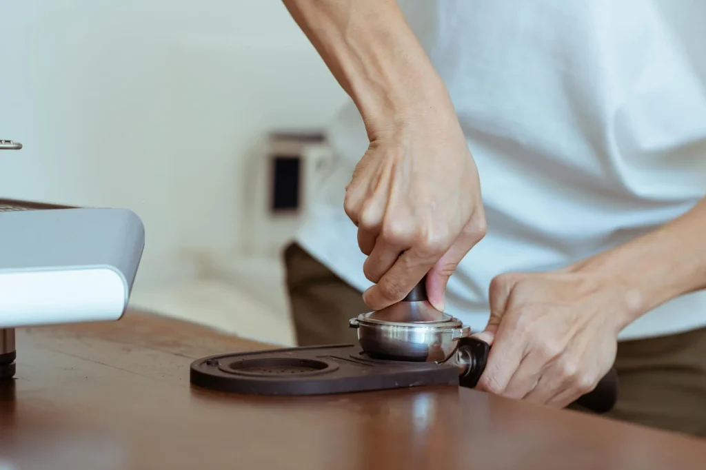 Coffee tamper pressing grounds in an espresso portafilter