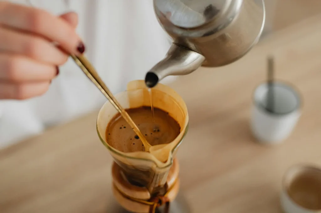 Pour-over coffee brewing with a glass carafe in morning light