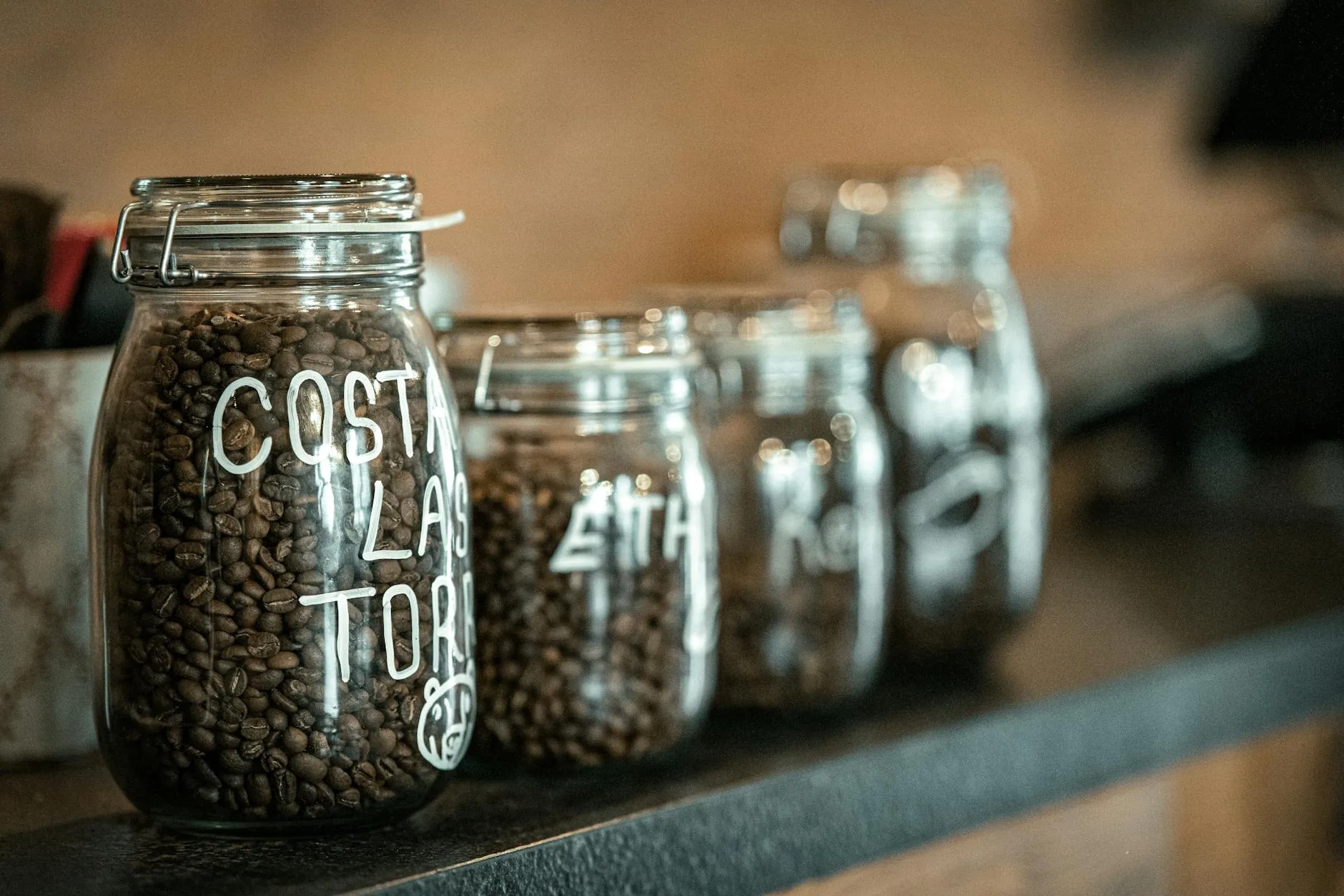Coffee beans stored in an airtight glass jar on a kitchen shelf