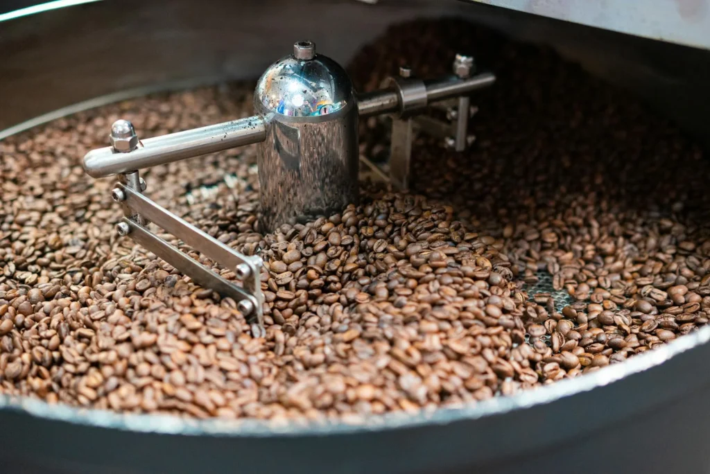 Freshly roasted coffee beans spilling from a bag beside an espresso machine