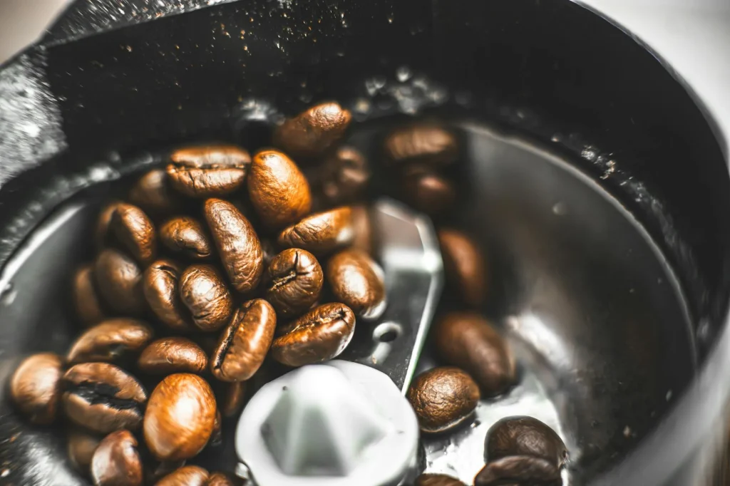 Coffee grinder with freshly ground beans showing burr mechanism