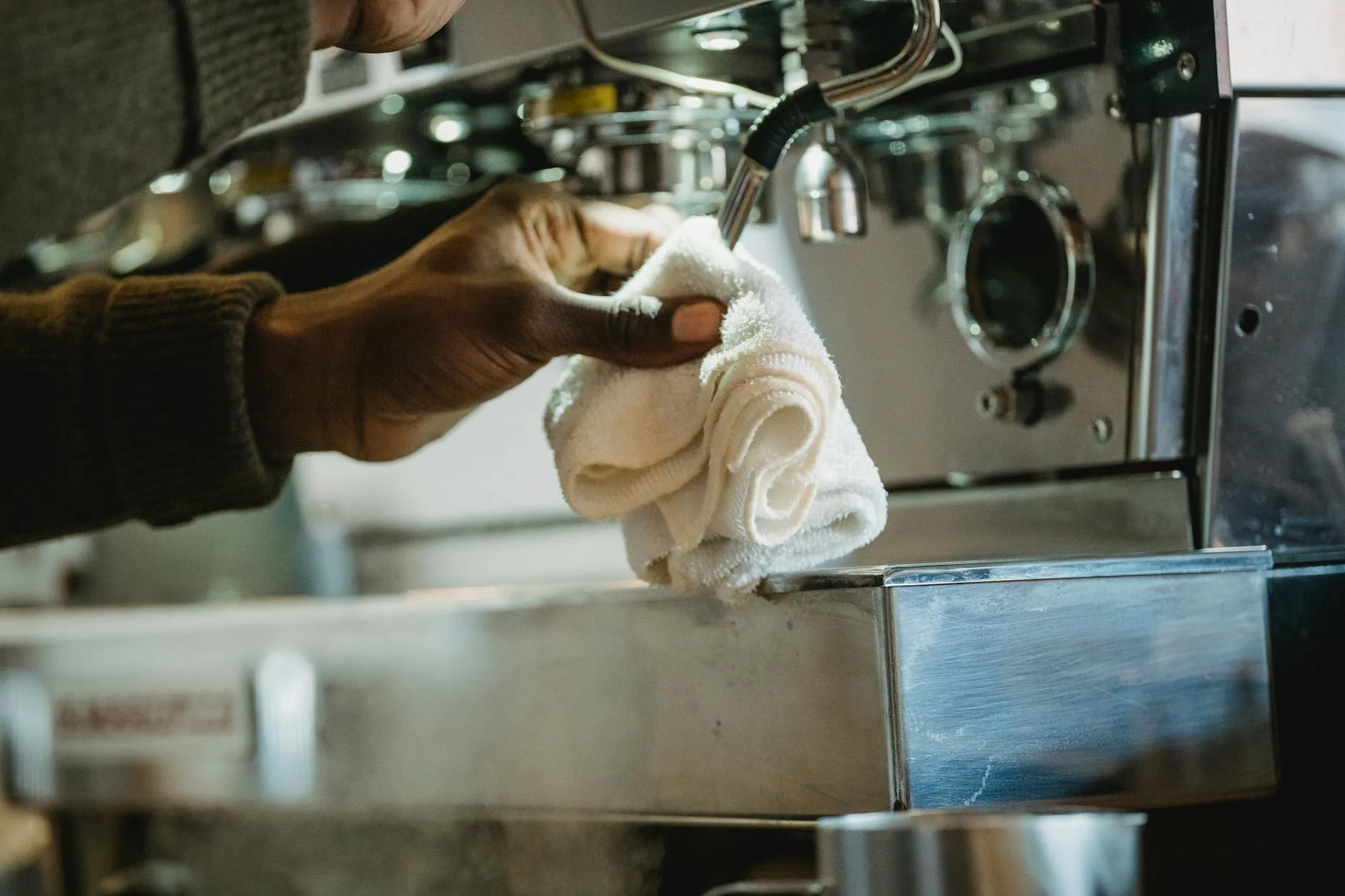 Barista cleaning an espresso machine with a cloth