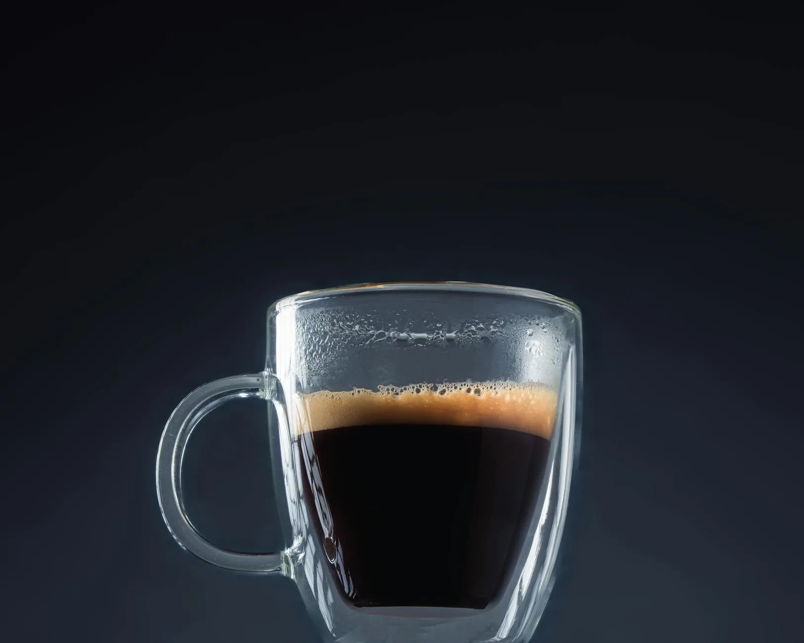 Fresh espresso shot in a glass with golden crema on top