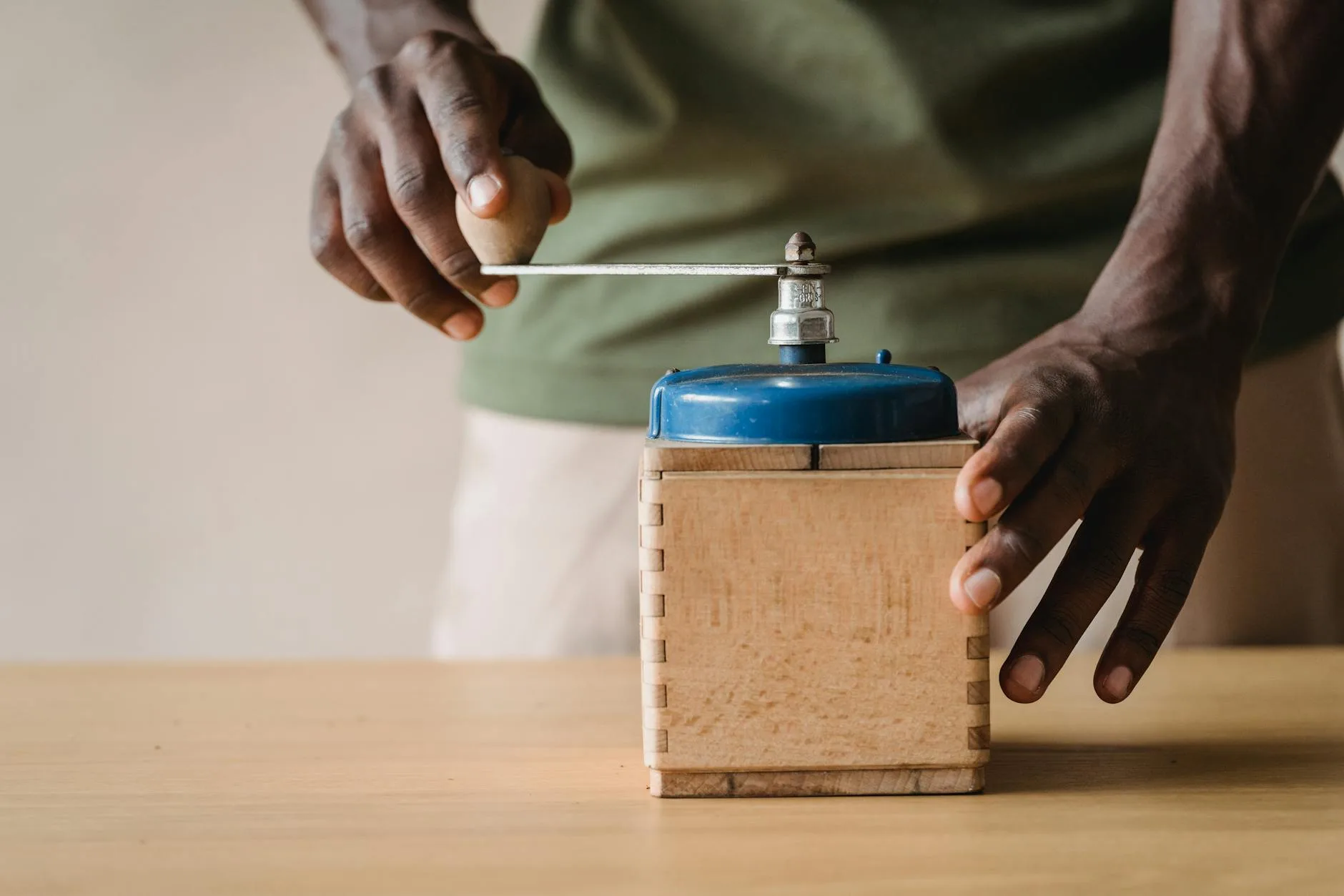 Person using a hand coffee grinder in a kitchen setting
