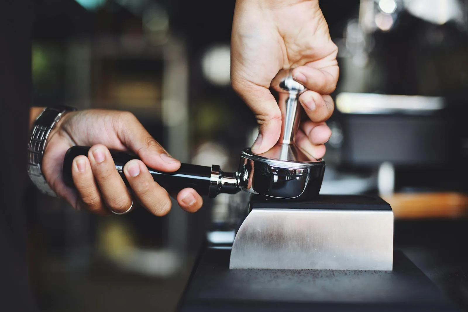 Barista tamping coffee grounds in portafilter before espresso extraction