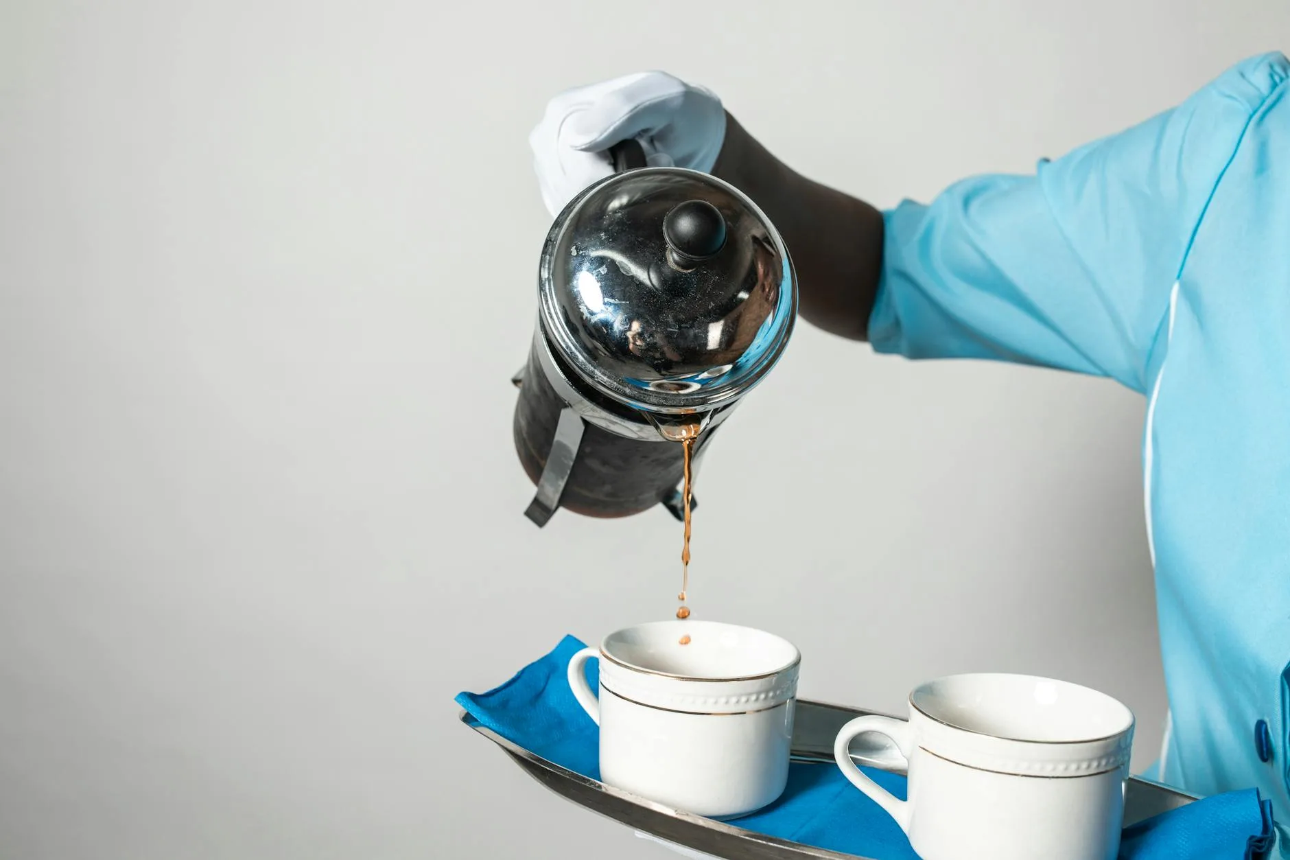 Pouring brewed coffee from a French press into a mug