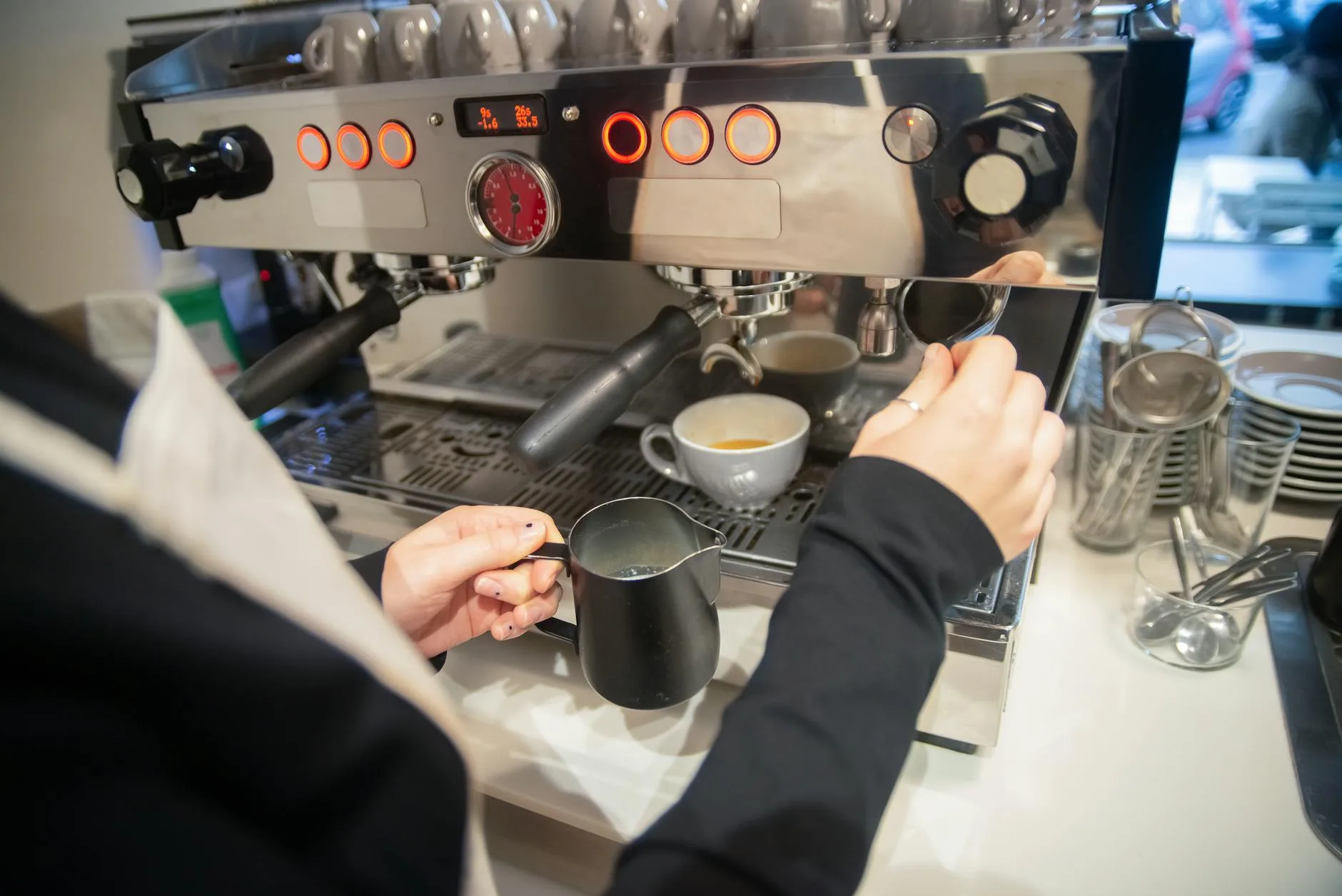 Steam wand on espresso machine frothing milk in a stainless steel jug