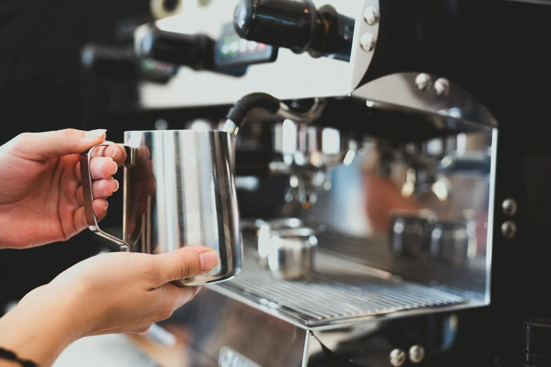 Steaming milk in a jug for latte art on a coffee machine