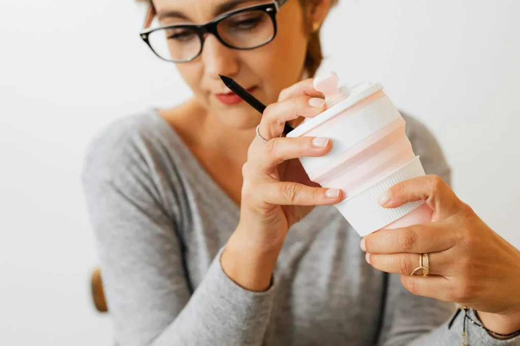 Person holding a reusable coffee cup outdoors