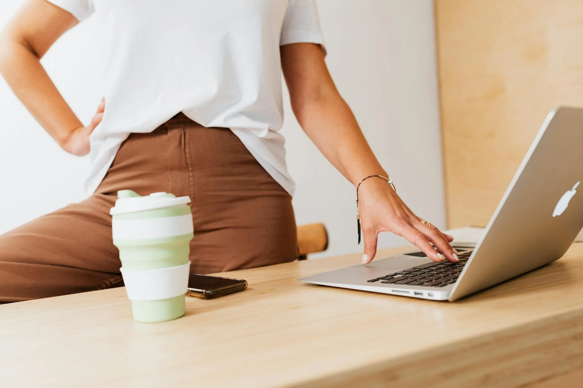Reusable coffee cup on a wooden desk beside a laptop