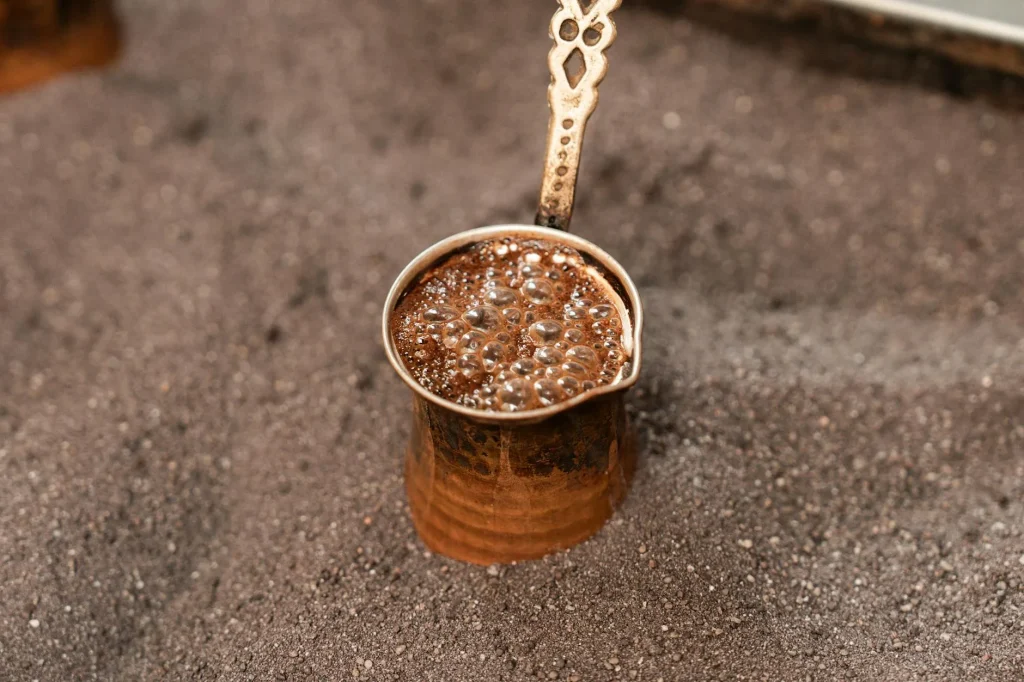 Turkish coffee in a cup with a copper cezve pot beside it