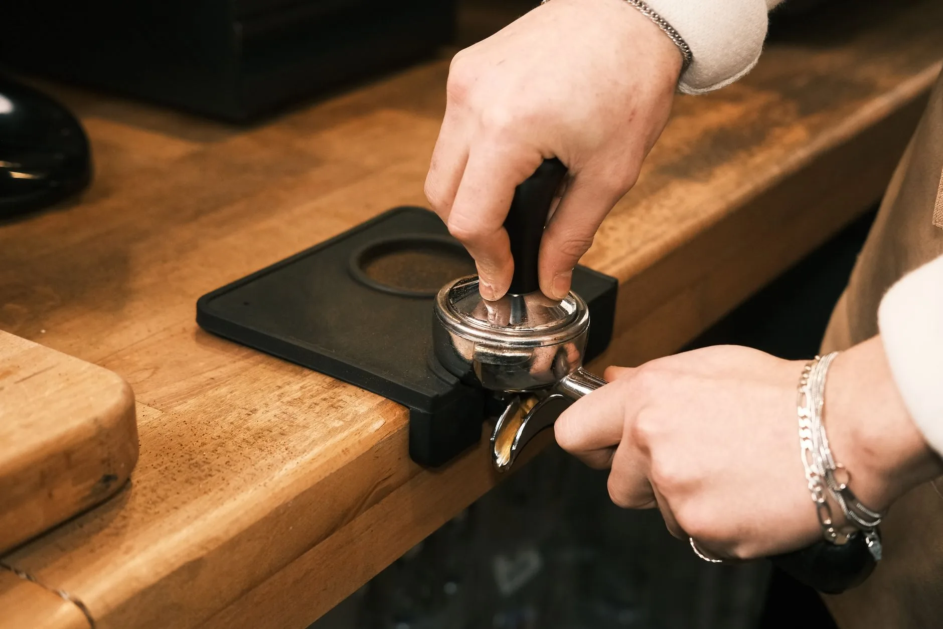 Tamping espresso in a portafilter beside a home coffee machine