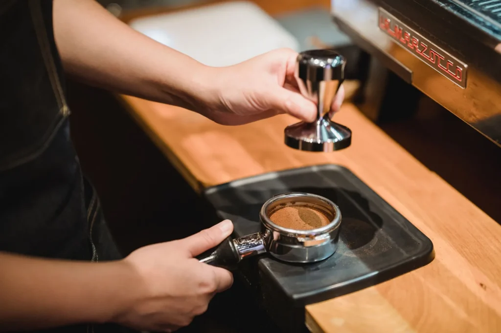 Espresso distribution tools beside a portafilter on a coffee bar