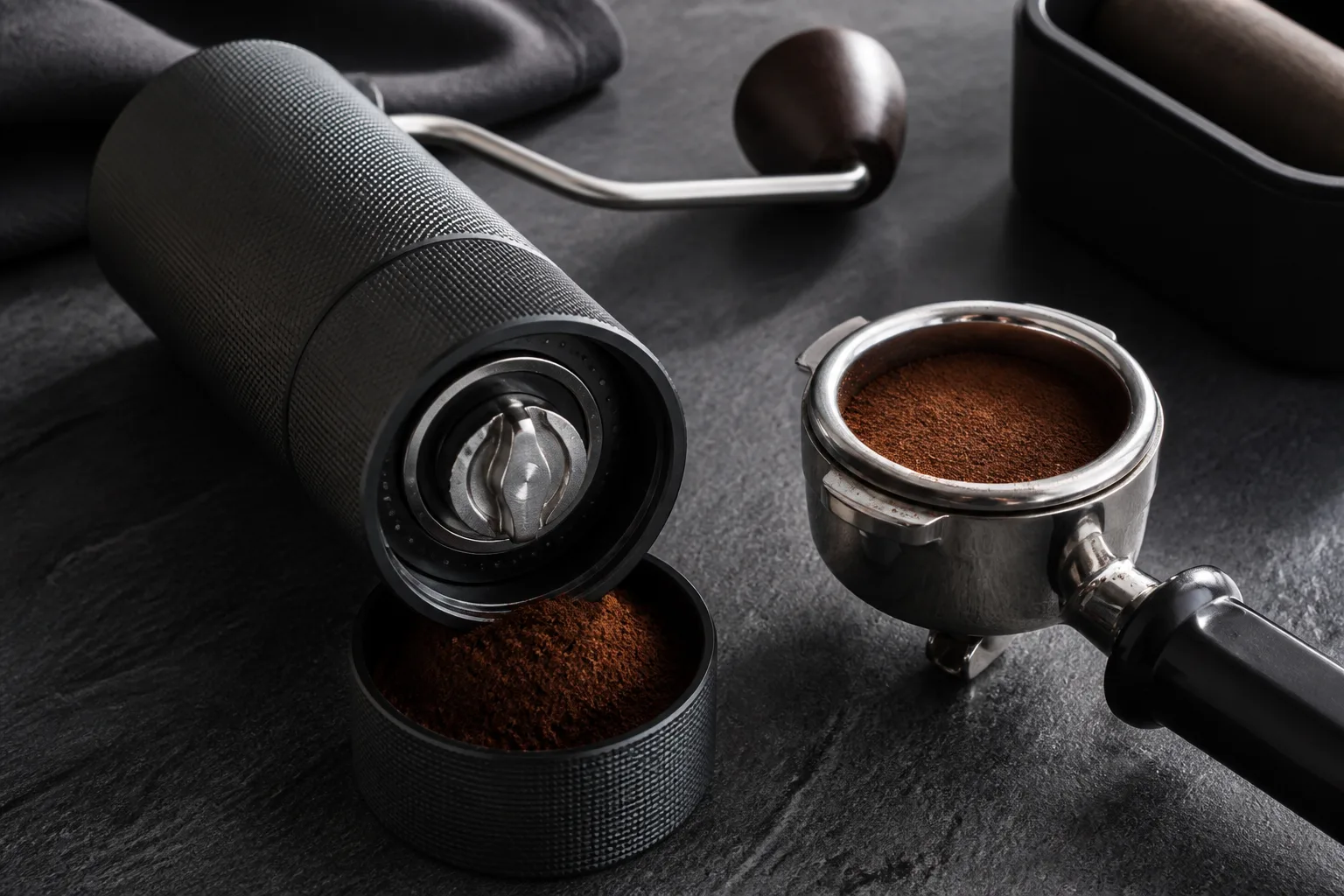 Manual coffee grinder adjustment dial beside an espresso portafilter
